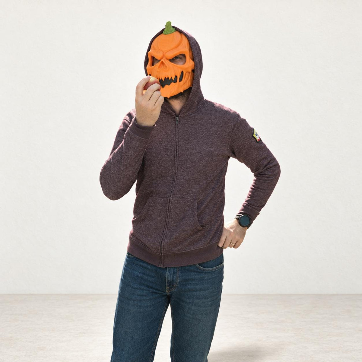 Pumpkin skull mask worn with a hoodie, three-quarter view