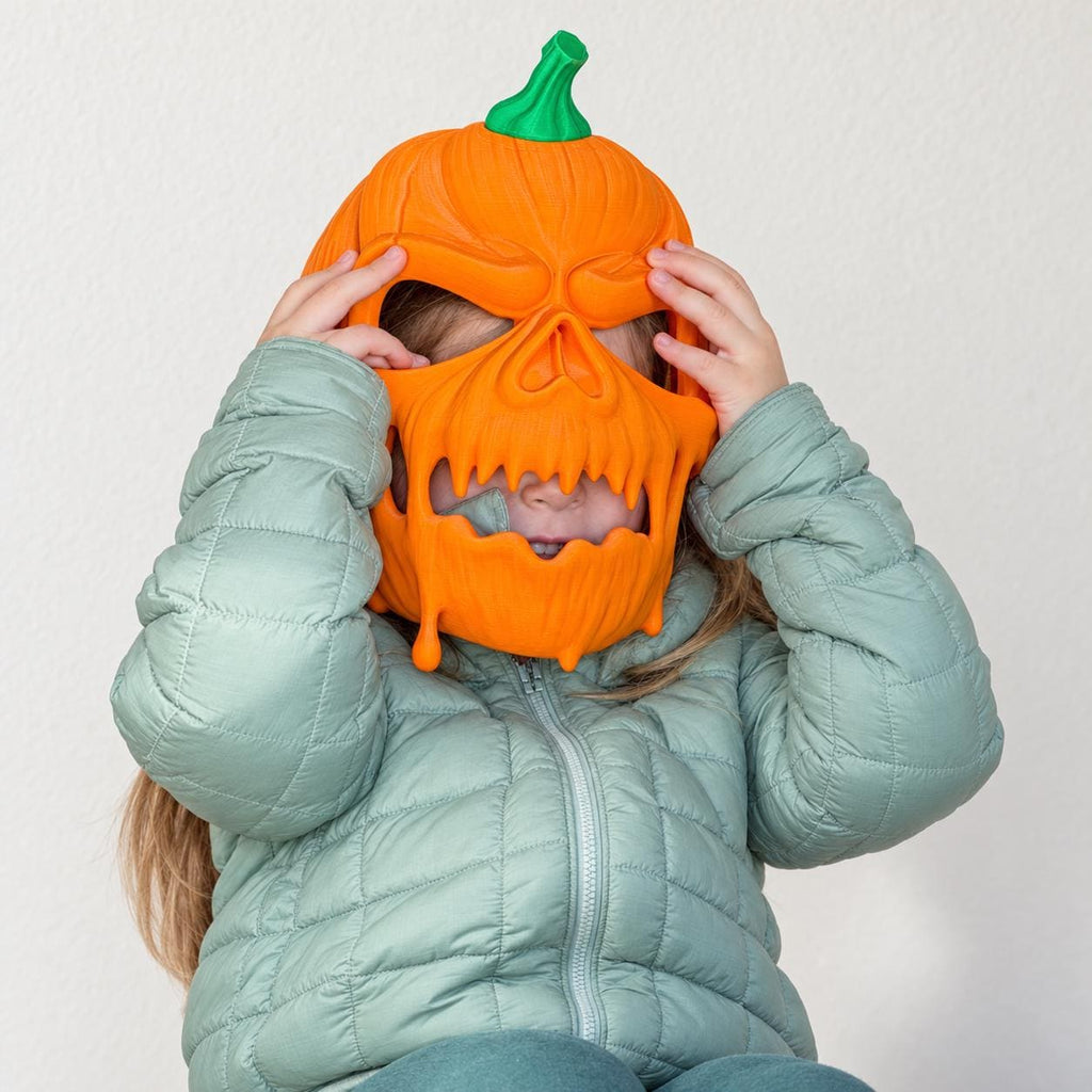 Pumpkin skull mask held up to a child's face for scale